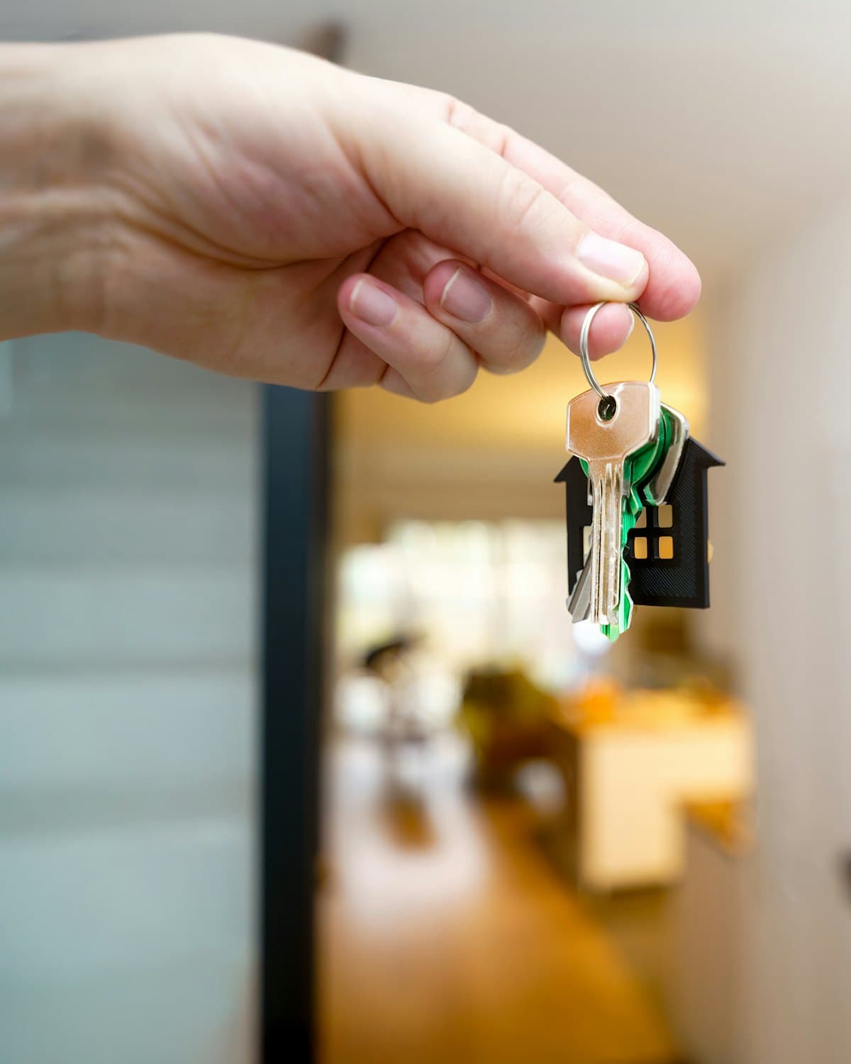A hand holding a set of house keys in front of an open door